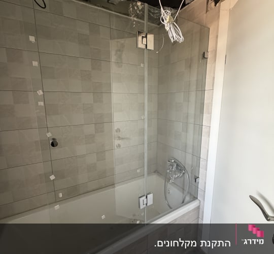 חדר אמבטיה עם מקלחון זכוכית ותקרה פתוחה